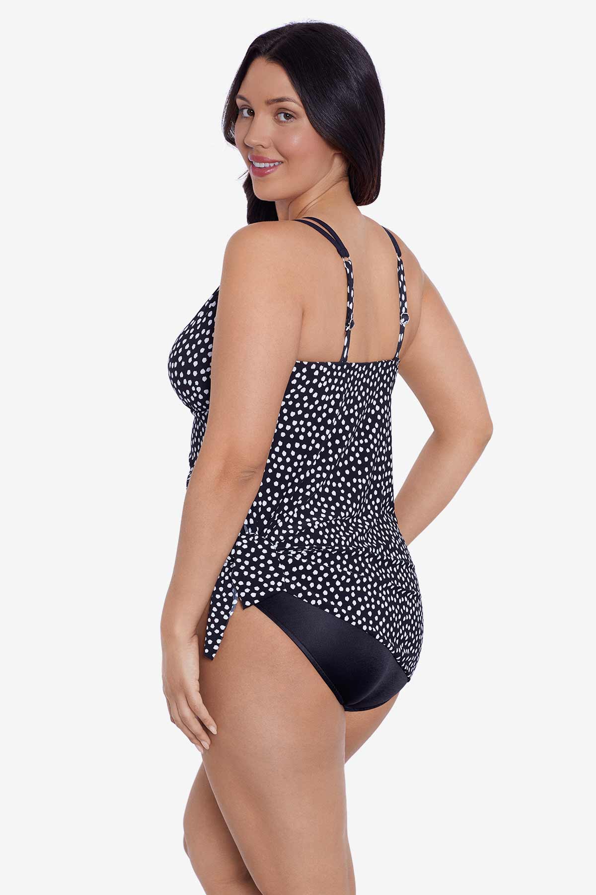 Woman turned left wearing a black and white polka dot swim dress tied at the side