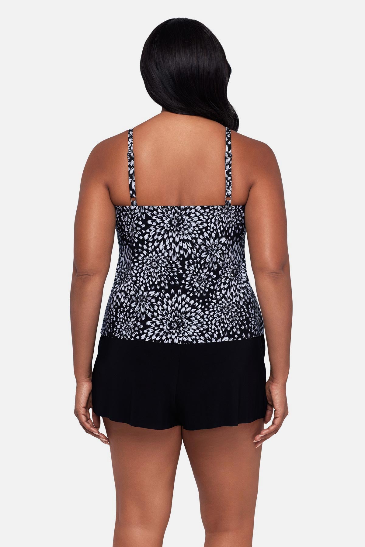 Woman turned away wearing a black and white floral printed swim romper