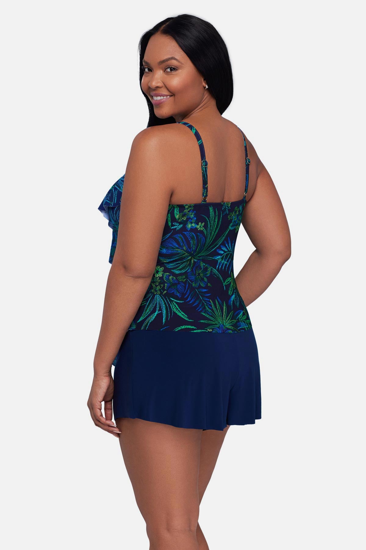 Woman turned left wearing a blue and green jungle printed tankini top with ruffles