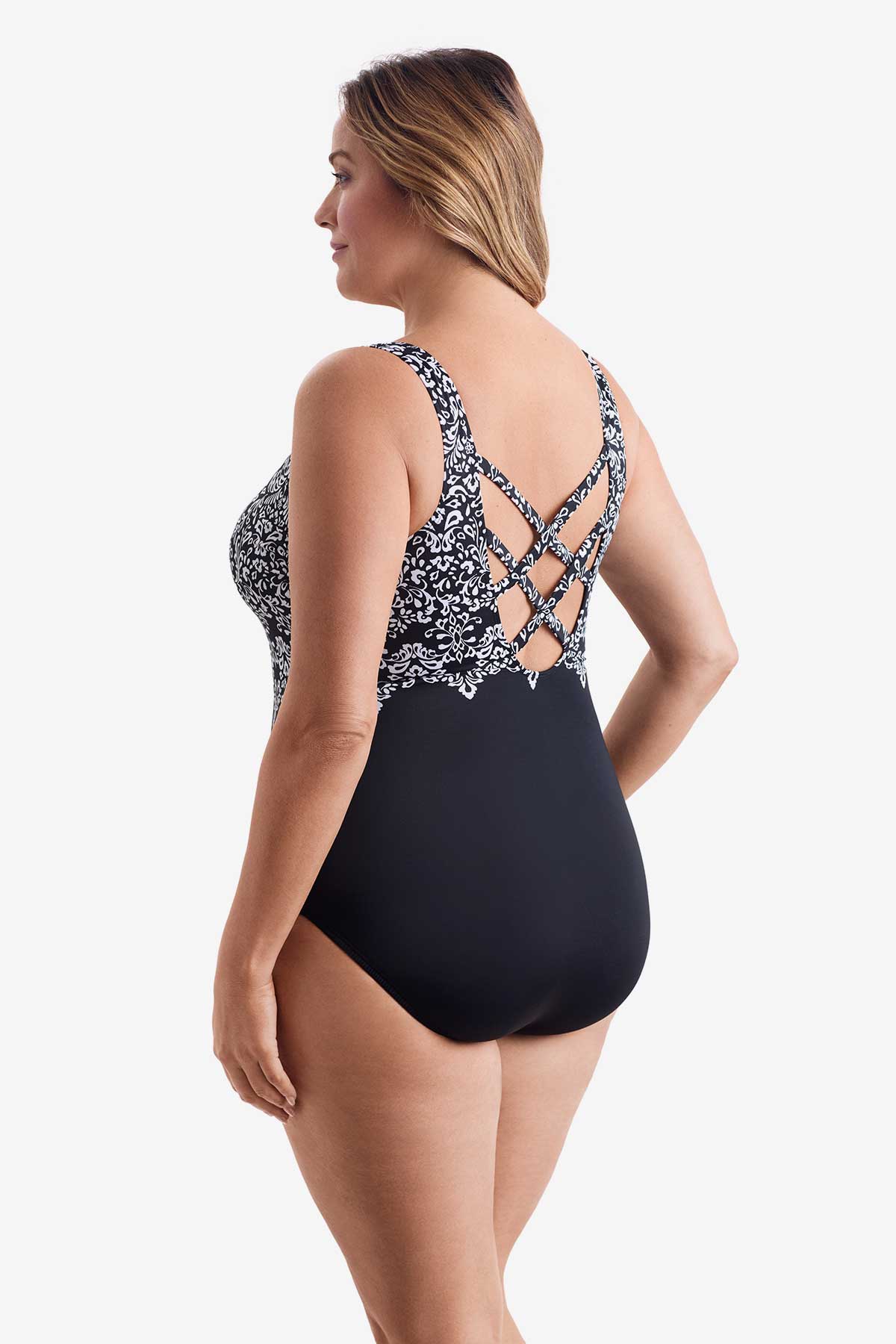 Woman turned left wearing a one-piece swimsuit with a black and white pattern on the bust