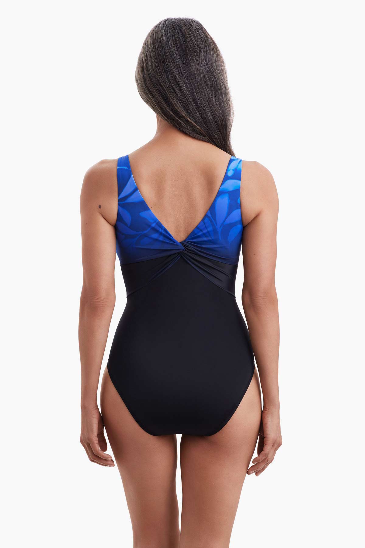 Woman faced away wearing a one-piece swimsuit with a faded print