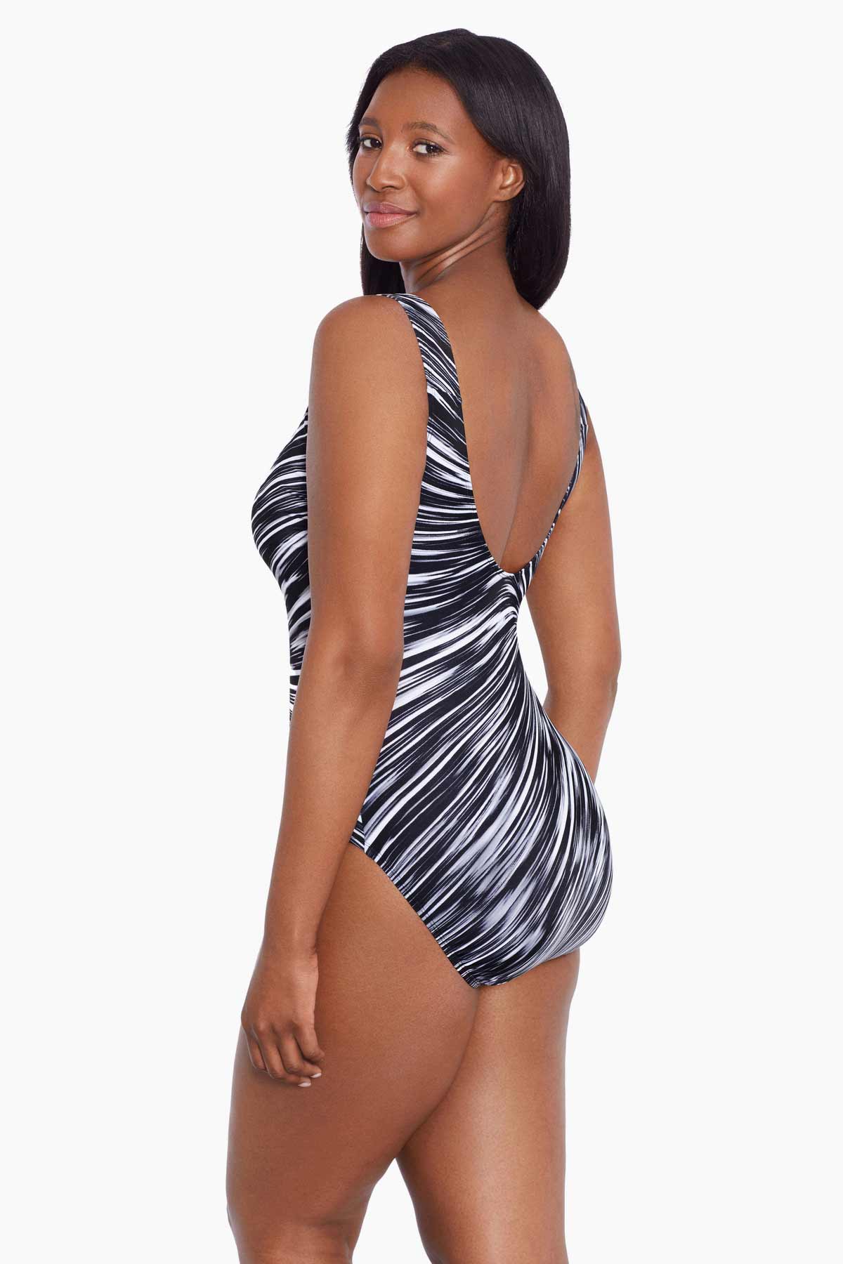 Woman turned left wearing a black and white radial printed one-piece swimsuit