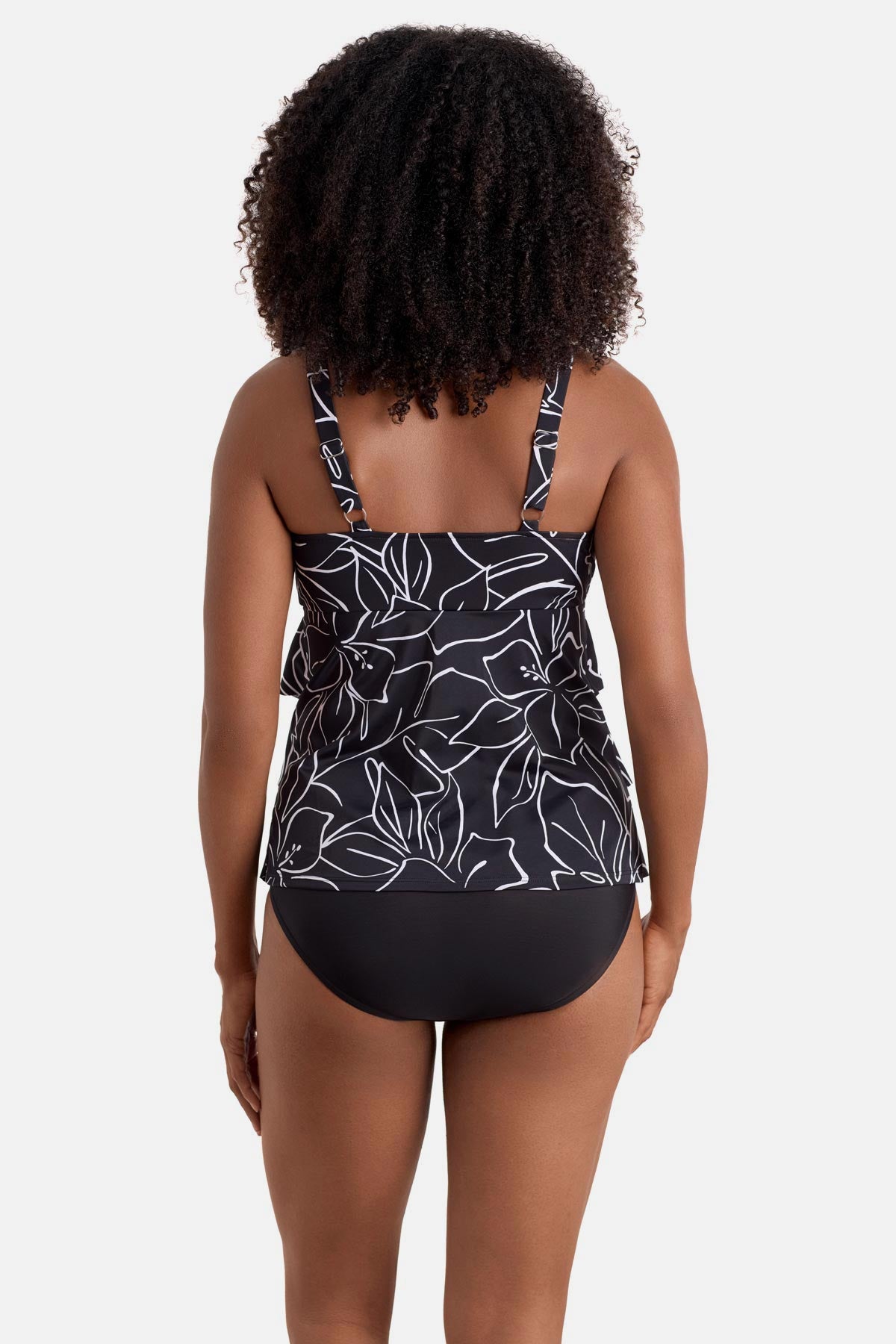 Woman turned away wearing a black and white floral outline print tankini top with ruffles