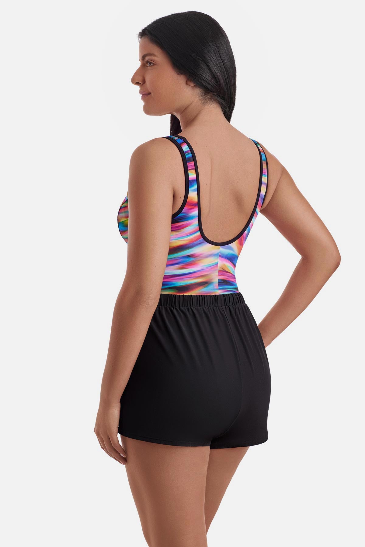 Woman turned left wearing a rainbow tie dye one-piece swim romper