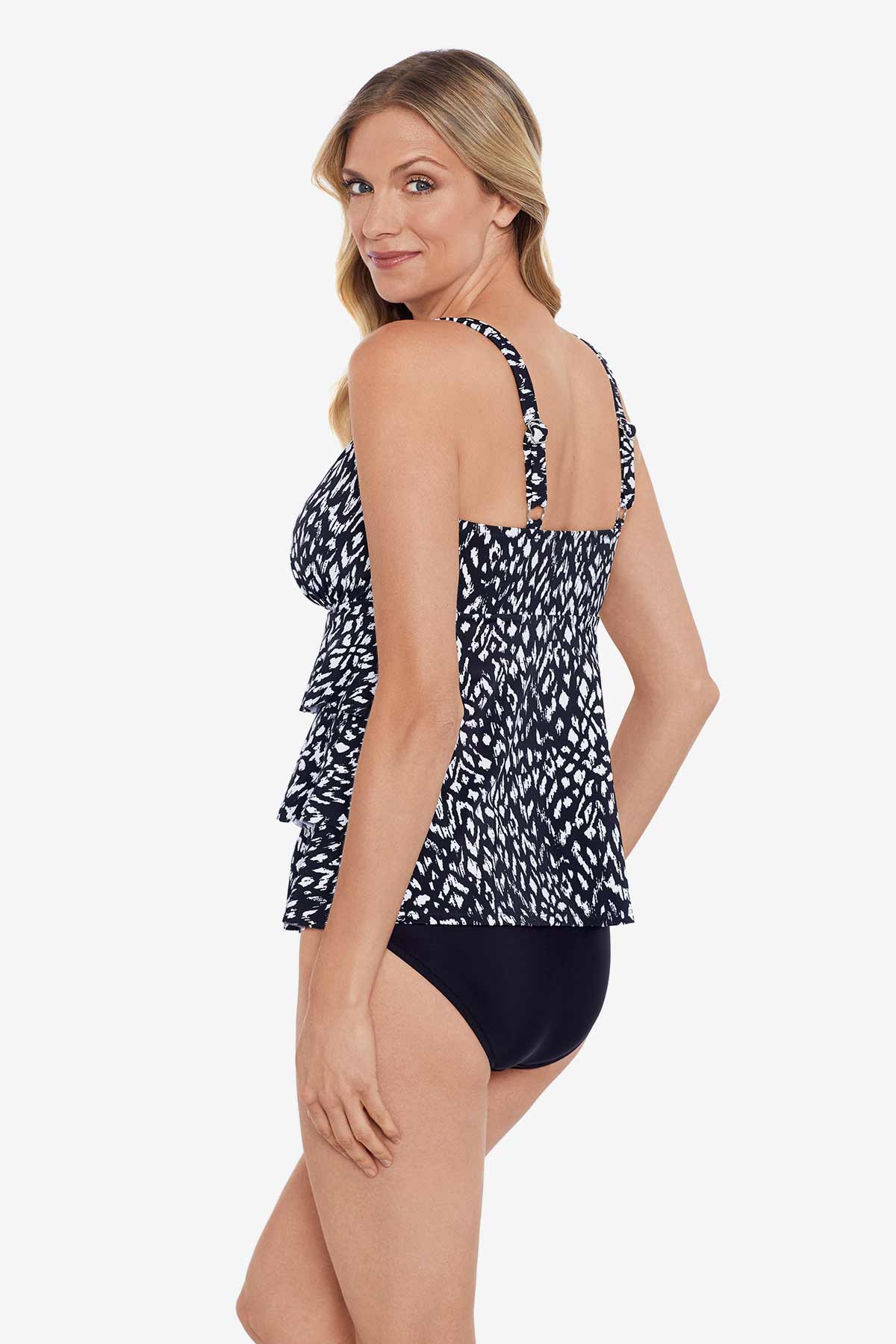 Woman turned left wearing a black and white scaley printed tiered tankini top