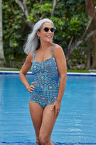 Woman in pool wearing a blue tile pattern one-piece swimsuit with a sweetheart neckline