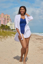 Woman on beach wearing a white shirt dress swim cover up