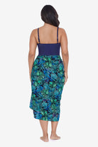 Woman faced away wearing a palm leaf printed swim wrap cover up with tassels