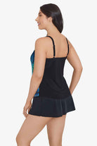 Woman turned left wearing a blue and black palm leaf and tile printed tankini top