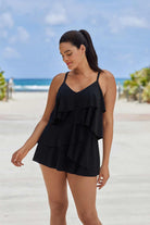 Woman on beach wearing a black ruffle swim dress