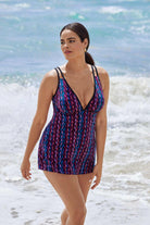 Woman on beach wearing a purple and blue stripey pattern swim dress tied at the side