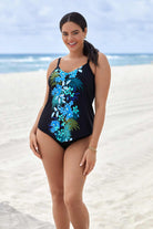 Woman on beach wearing a black tankini top with a blue floral pattern down the front