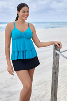 Woman on beach wearing a light blue tiered tankini top