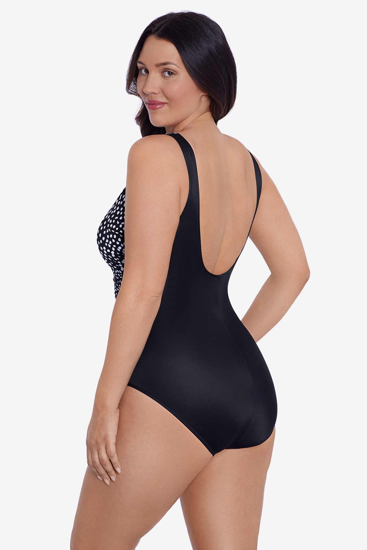 Woman faced left wearing a black and white polka dot one-piece swimsuit