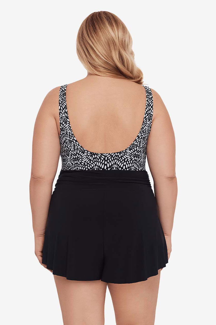 Woman faced away wearing a black and white lace-esque pattern swim romper