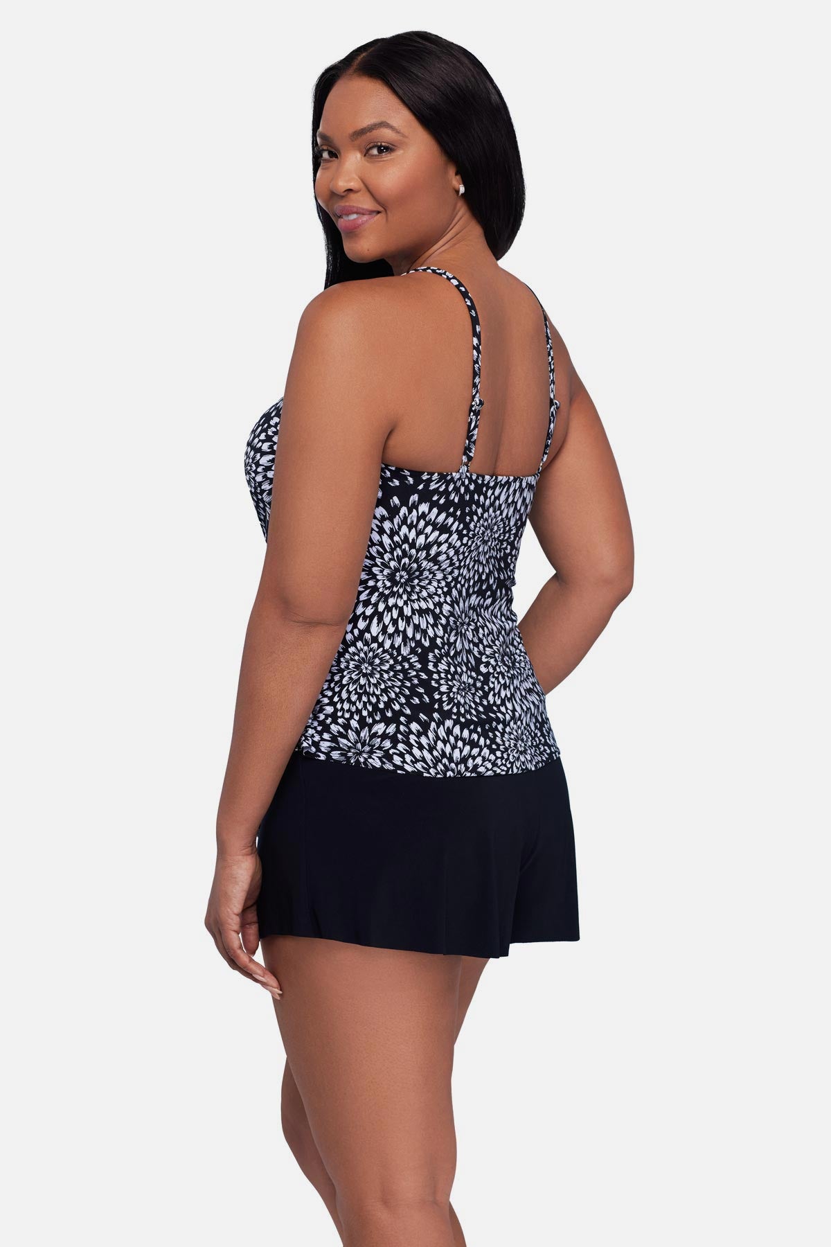 Woman turned left wearing a black and white floral printed tankini top with ruffles