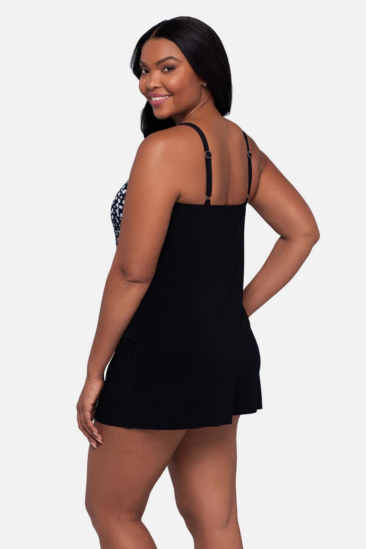 Woman turned left wearing a black and white dot printed romper swimsuit
