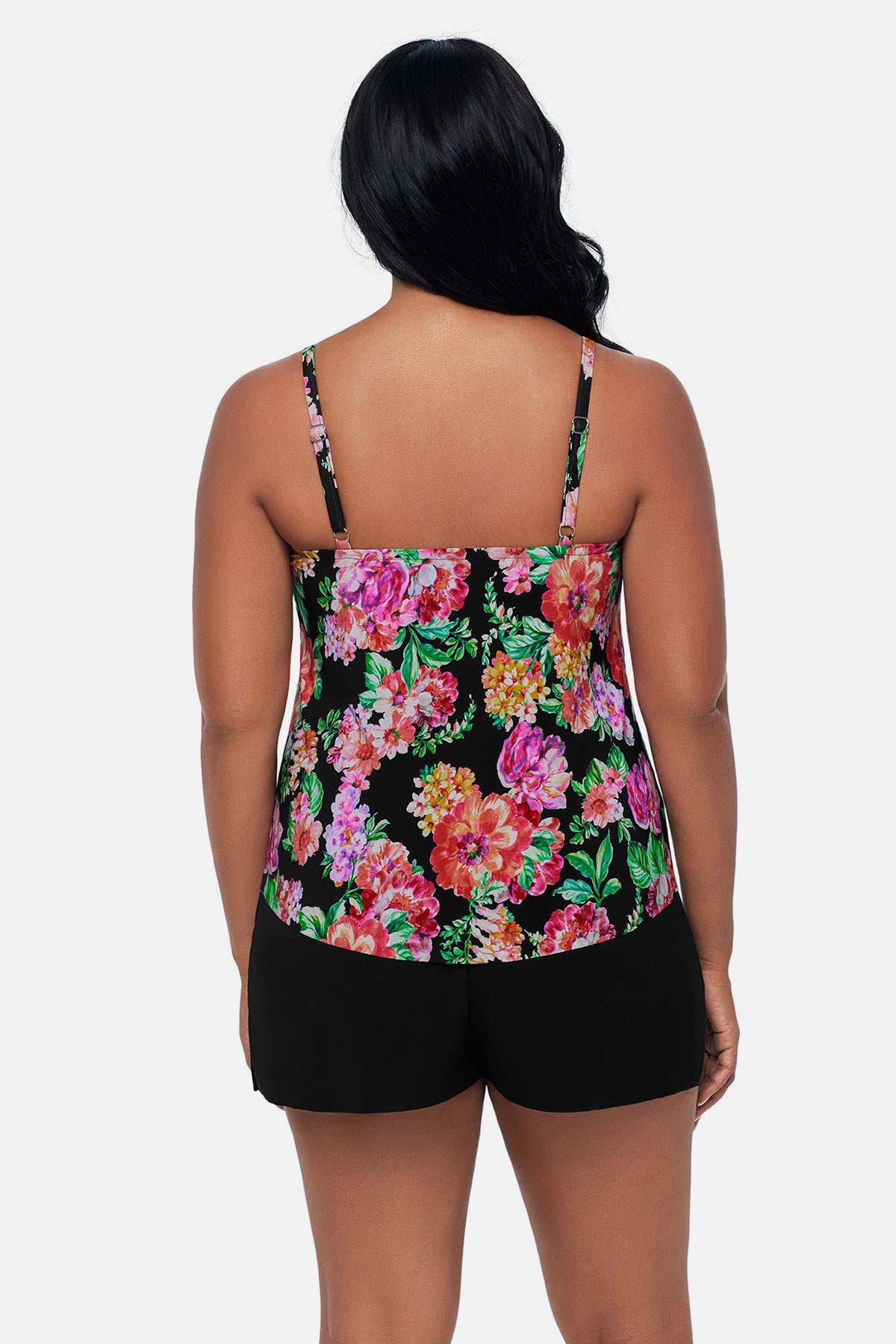 Woman turned away wearing a pink and orange floral printed swim romper