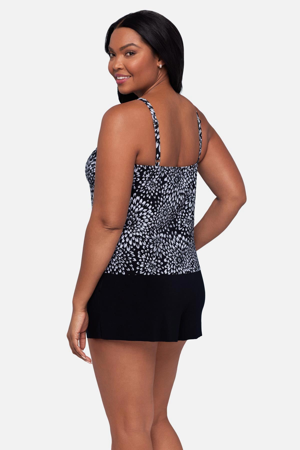 Woman turned left wearing a black and white floral printed swim romper