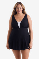Woman wearing a black swim dress with a white panel on the bust