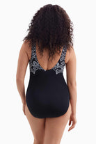 Woman faced away wearing a black and white garland printed one-piece swimsuit