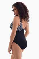 Woman turned left wearing a black and white garland printed one-piece swimsuit