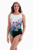 Woman wearing half white half black one-piece swimsuit with a floral print running through the middle