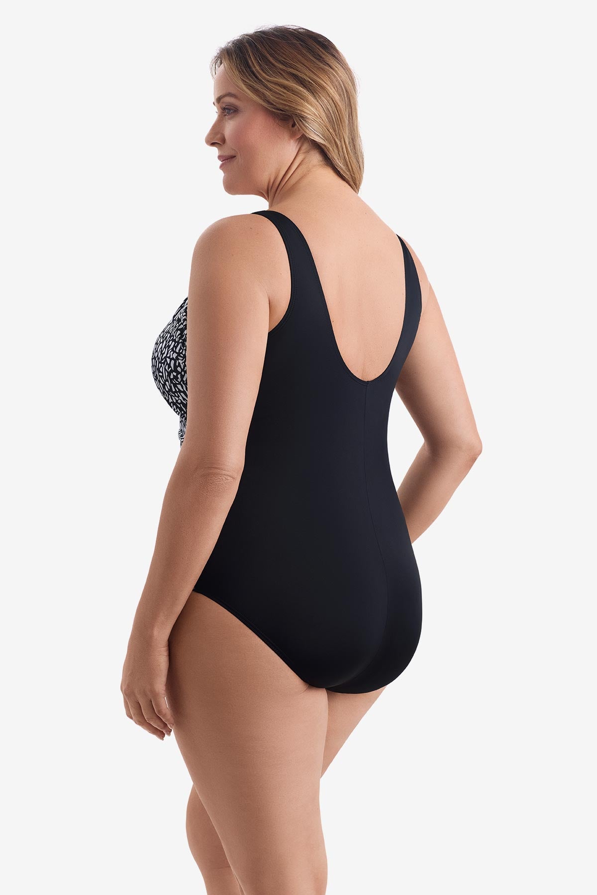 Woman turned left wearing a black and white paper mache printed one-piece swimsuit