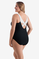 Woman turned left wearing a black one-piece swimsuit with white on the X back