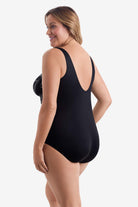 Woman faced left wearing a black and white leaf printed one-piece swimsuit