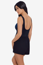Woman turned left wearing a black and blue faded dot print romper one-piece swimsuit