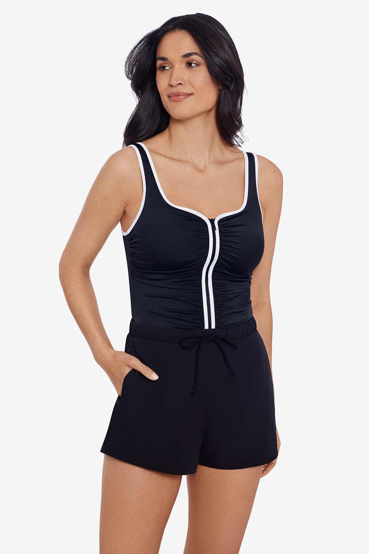 Woman wearing a black romper swimsuit with white piping down the front and on the straps