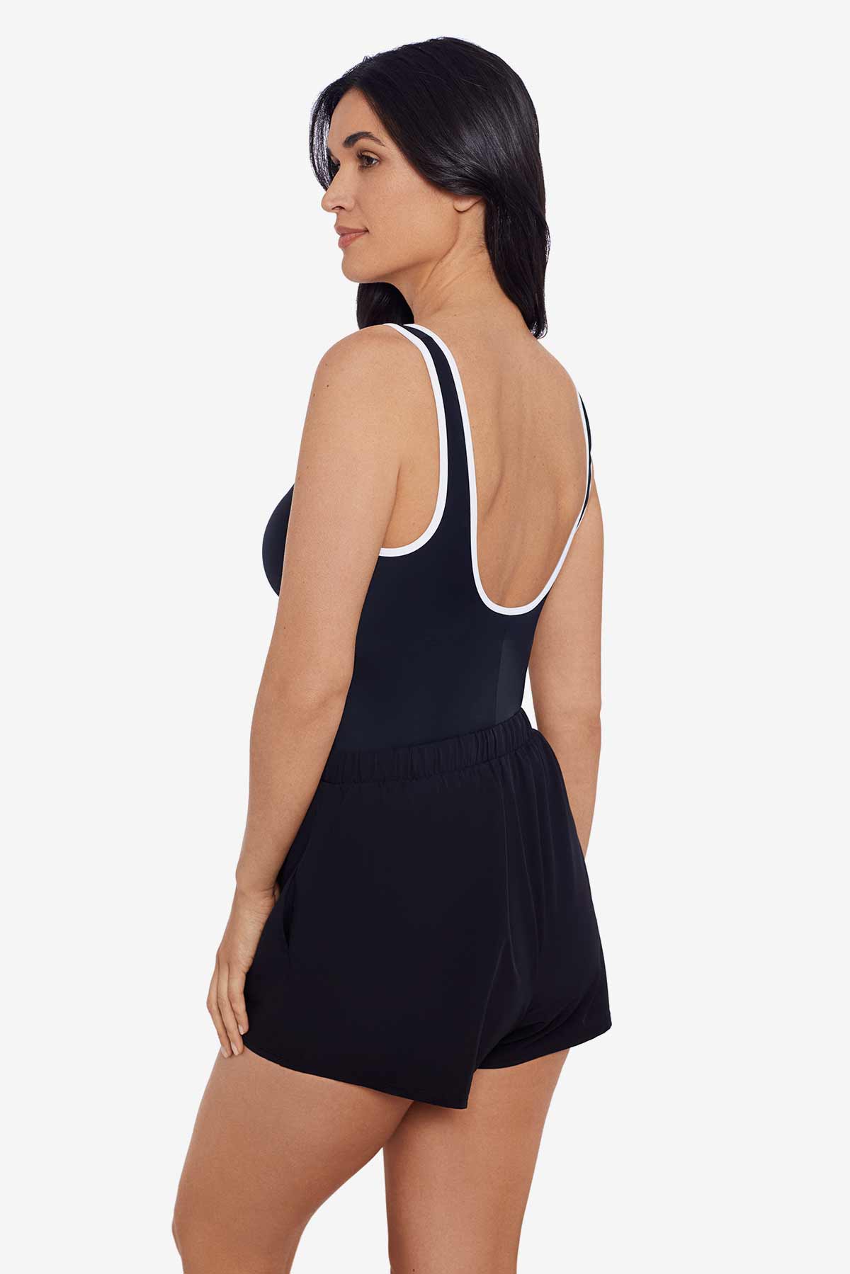 Woman faced left wearing a black romper swimsuit with white piping on the straps
