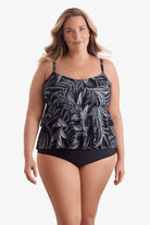 Woman wearing a black and white leaf pattern tankini top with tiered ruffles