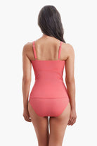 Woman faced away wearing a coral pink one-piece swimsuit 