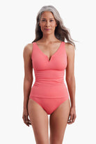 Woman wearing a coral pink one-piece swimsuit with a sweetheart neckline