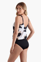 Woman facing left wearing a tankini top with a large black and white flower print