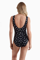Woman faced away wearing a polka dotted one-piece swimsuit 
