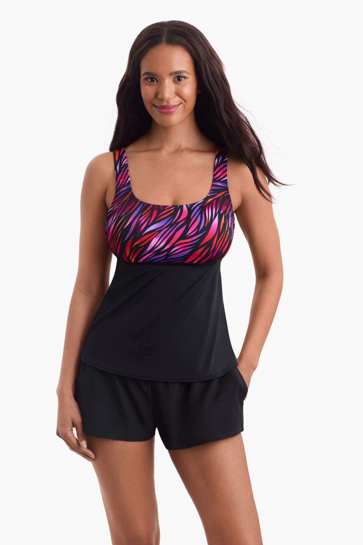Woman wearing a tankini swim top with a pink pattern on the bust with her hand in he pocket