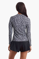 Woman faced away to show detail of the black and white print on the sun shirt