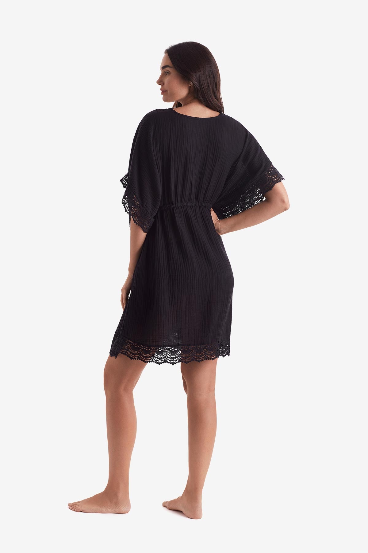 Woman turned left wearing a black tunic dress
