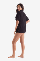 Woman laced left wearing a black short sleeve button up shirt