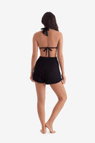 Woman turned away wearing a black bikini top and black shorts
