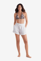 Woman wearing a zebra print bikini top with white beach shorts
