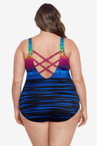 Woman faced away wearing a rainbow ombre with a geometric overlay print one-piece swimsuit