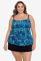 Woman wearing a black and blue petal pattern ruffle faux skirtini one-piece swimsuit
