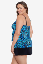 Woman turned left wearing a black and blue petal pattern ruffle faux skirtini one-piece swimsuit