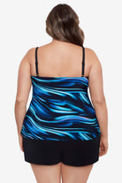 Woman turned away wearing a black and blue oil slick print ruffle tiered one-piece swimsuit shortini