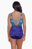 Woman turned away wearing a blue abstract printed one-piece swimsuit with X back 