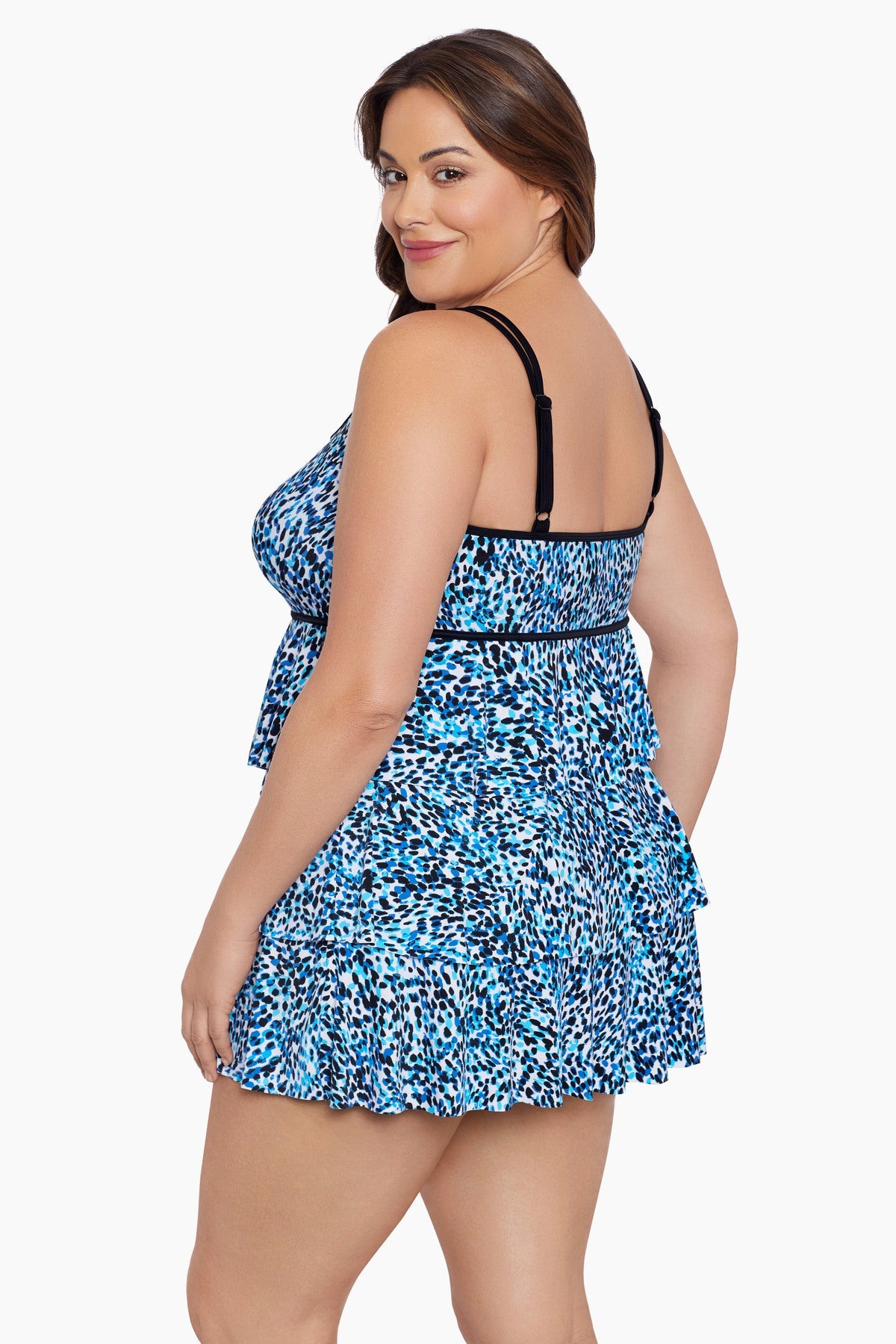 Woman turned left wearing a multi-blue speckled swim dress with tiered ruffles
